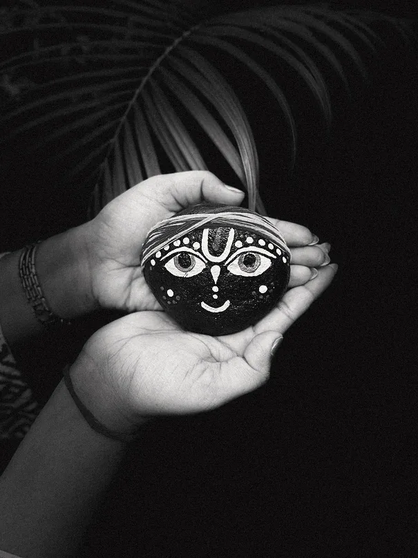 Black and white close-up of hands holding a hand-painted stone