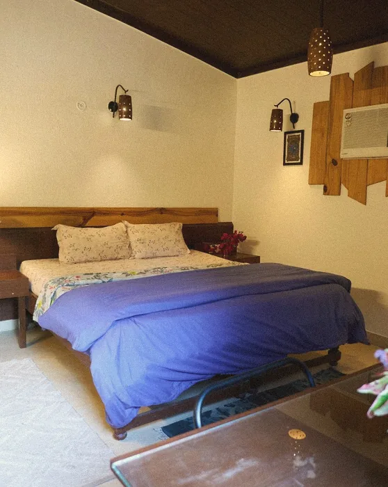 Cottage bedroom with a wooden bed, blue bedspread and warm wall lamps