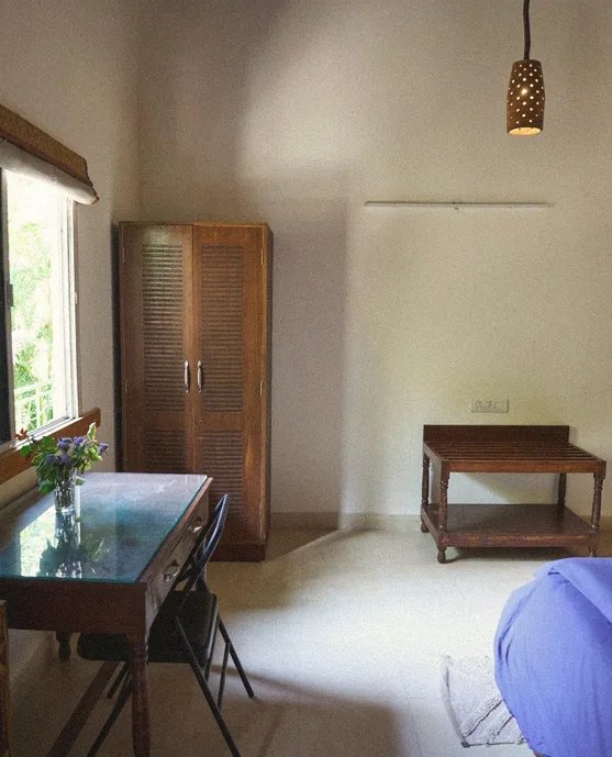 Simple cottage interior with a wooden wardrobe, desk and woven pendant lamp
