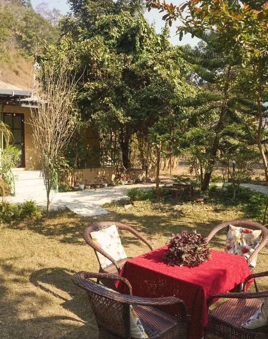 Wicker chairs around a red-clothed table in the garden