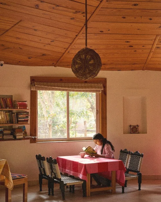Guest reading at a red-checked table in the wood-ceilinged common room