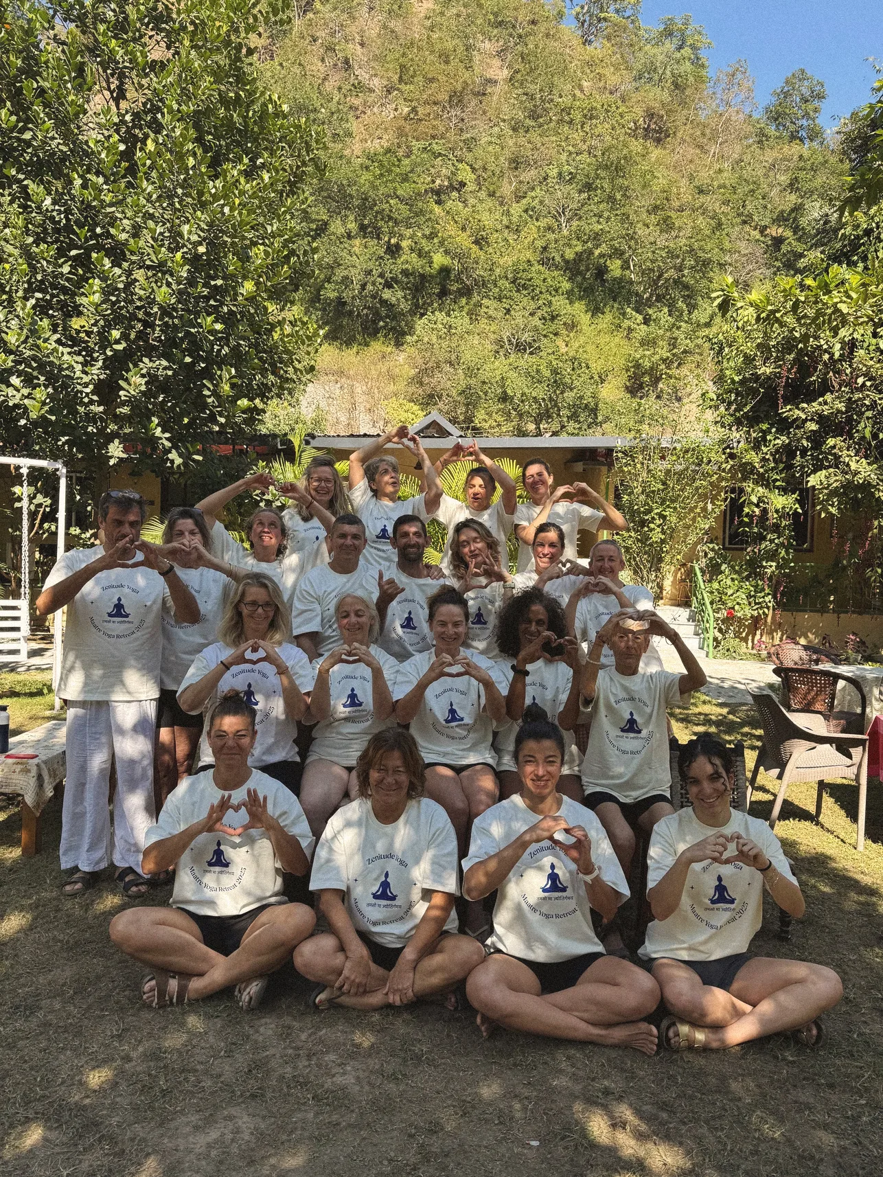Yoga retreat group in matching tees making heart shapes with their hands