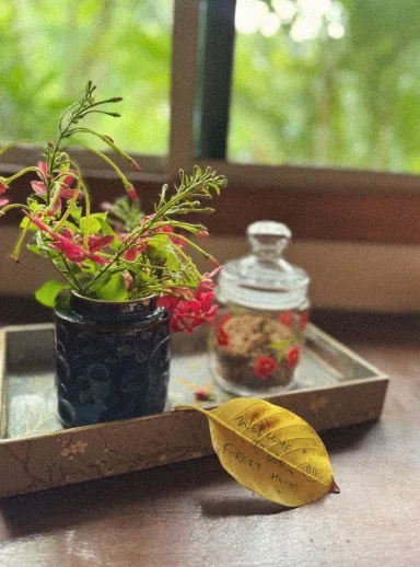 Wildflowers in a blue vase with a handwritten leaf on a tray by the window