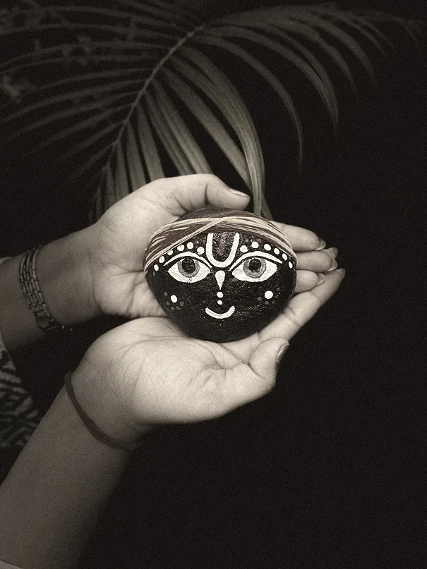 Black and white close-up of hands holding a hand-painted stone