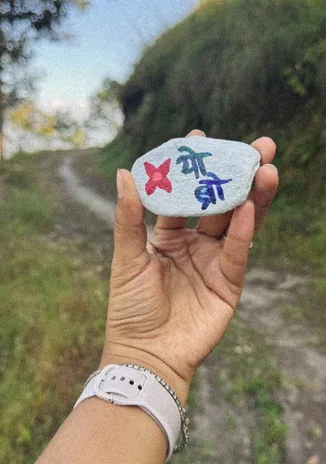 Hand holding a painted stone on a forest trail