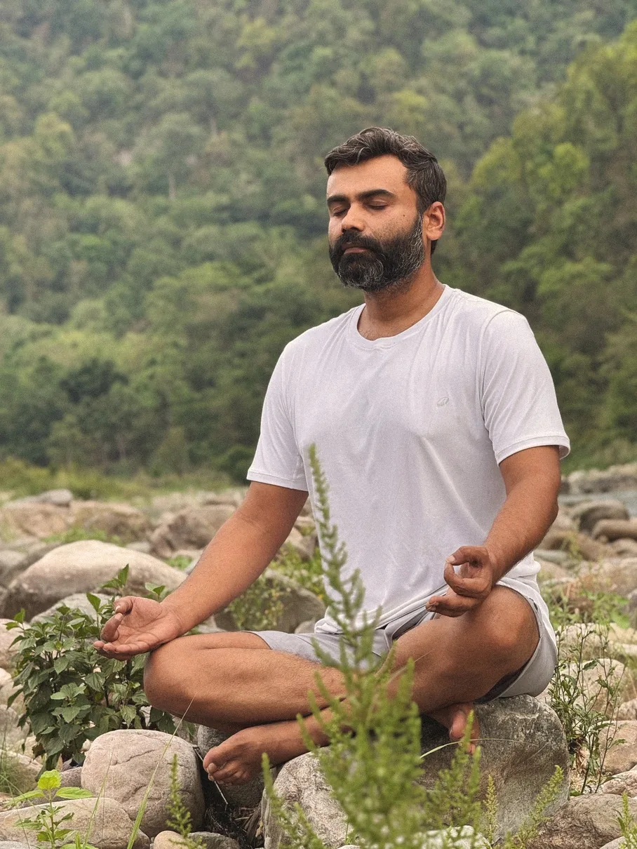 Navendu meditating cross-legged on the riverbank