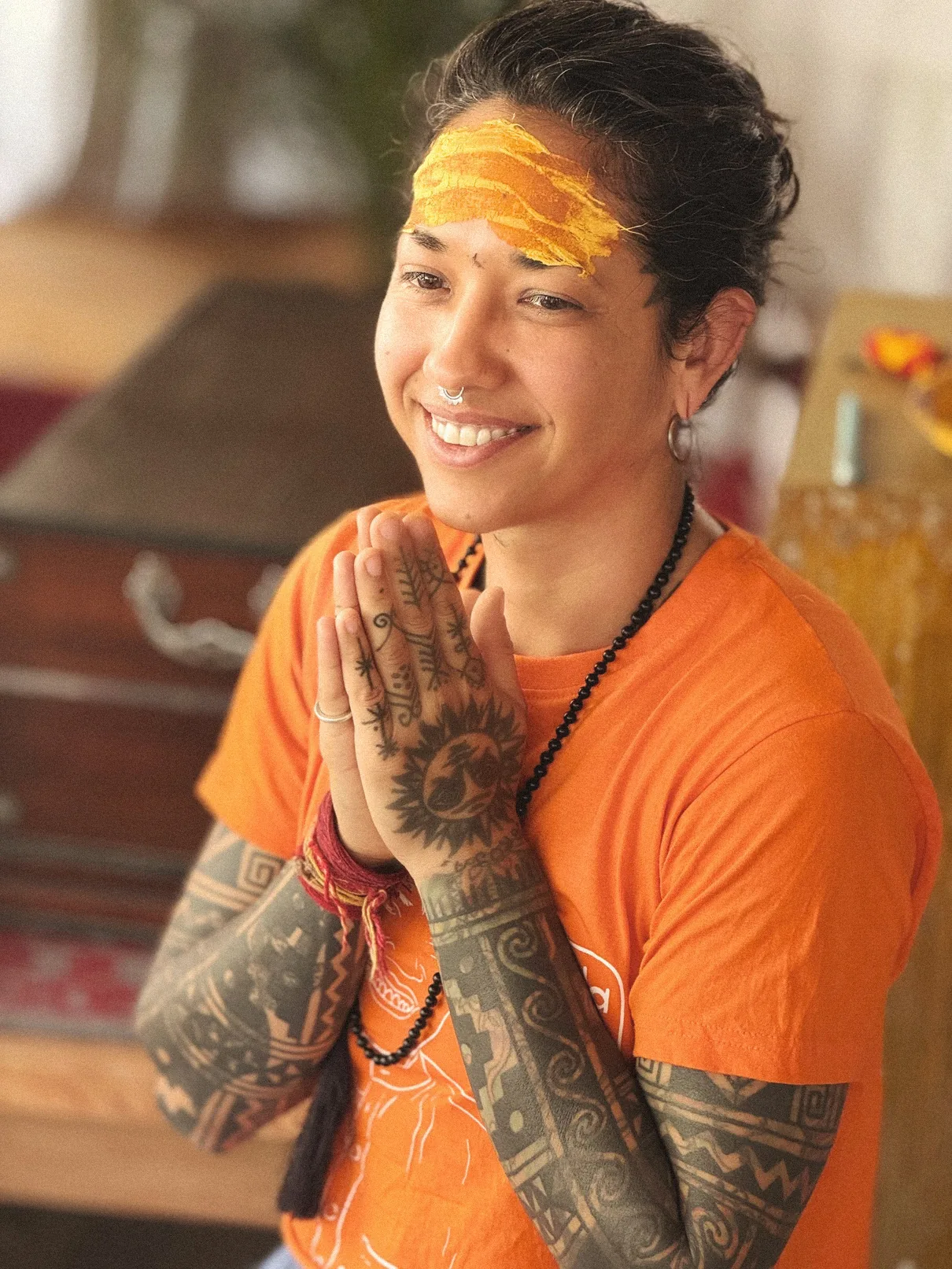 Smiling guest with a turmeric tilak and hands in namaste