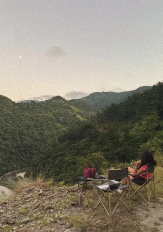 Camp chairs on a hilltop at sunset overlooking the valley