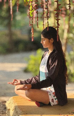 Woman meditating on a stone by the river