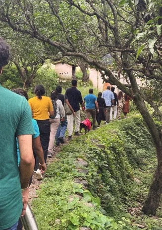Group walking a narrow village trail through the trees